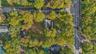 Aerial perspective of a corner lot featuring extensive lawn space, mature perimeter trees, and a detached structure