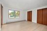 Interior space featuring light wood-finish flooring, two sets of full-height wood-finish sliding closet doors, and a double-pane window