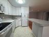 Eat In Kitchen featuring white cabinetry, mosaic tile backsplash, breakfast bar with solid surface countertop, and ceramic tile flooring