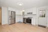 Kitchen featuring white cabinetry, stainless steel appliances, wood-finish flooring, a farmhouse-style sink faucet, and a paneled exterior door with g