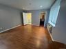 Room featuring wood-finish flooring, recessed lighting, horizontal window blinds, and a built-in wall air conditioning unit