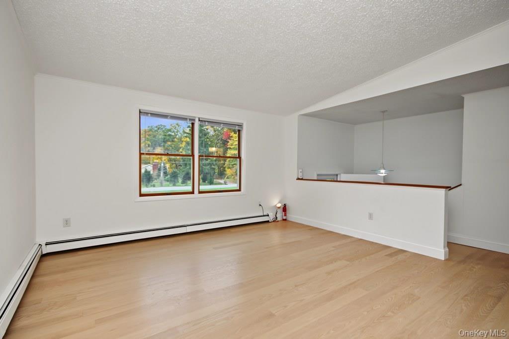 Interior space featuring wood-finish flooring, a double-pane window, and a half-wall with a wooden cap