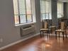 Interior space featuring wood-finish flooring, full-wall mirrors, large windows, and a built-in wall-mounted climate control unit