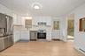 Kitchen featuring white cabinetry, stainless steel appliances, wood-finish flooring, a recessed sink with a pull-down faucet, and a flush-mount light 