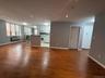 Open interior featuring wood-finish flooring, recessed lighting, white kitchen cabinetry, and large paneled windows