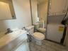 White vanity with integrated sink, porcelain toilet, and stacked laundry unit on tile flooring