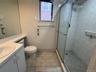 Bathroom featuring a walk-in shower with sliding glass doors, tile surround, and wall-mounted grab bars, complemented by a vanity with an integrated s