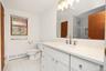 Bathroom featuring a white quartz vanity with a solid-surface countertop, an undermount sink, a brushed-metal widespread faucet, a large frameless mir