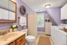 Bathroom featuring wood-finish vanity cabinetry, integrated sink with metallic faucet, medicine cabinet, dual-door wall-mounted storage, and tile floo