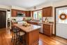 Kitchen featuring stained wood cabinetry, central island, laminate countertops, stainless steel appliances, and wood-finish flooring
