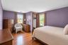 Bedroom featuring wood-finish flooring, two large windows, and a closet with wood trim