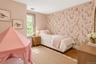 Room featuring wood-finish flooring, a single-hung window with casing, and a decorative floral-patterned accent wall