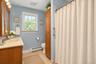 Full bathroom featuring wood-finish vanity cabinetry, a solid-surface countertop with an integrated basin, a floor-to-ceiling built-in storage cabinet