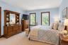 Spacious room featuring neutral carpeting, double-hung windows with stained wood trim, and light blue wall tones