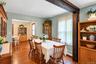 Dining space featuring wood-finish flooring, exposed stained wood structural beam, and natural light through large windows
