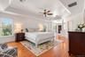 The spacious primary bedroom offers a peaceful private retreat, showcasing gleaming pinewood floors, distinctive tray ceilings with architectural soff