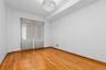Primary bedroom featuring wood-finish flooring, a decorative crystal-style chandelier, and a recessed ceiling design.