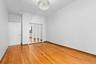 Wood-finish flooring, mirrored closet doors, overhead crystal-style chandelier, and built-in upper storage cabinetry.