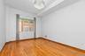 Primary bedroom featuring wood-finish flooring, a tiered ceiling, and a multi-tiered crystal chandelier fixture.