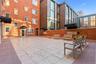 Shared Outdoor courtyard featuring large-format stone pavers, a perimeter brick wall, and dark metal awnings