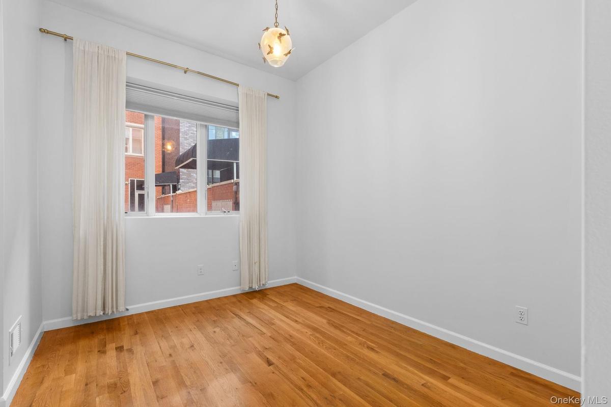 Room featuring wood-finish flooring, a multi-pane window, and a hanging pendant light fixture