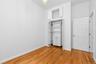 Interior room featuring wood-finish flooring, white walls, and a built-in closet system with integrated shelving and drawers