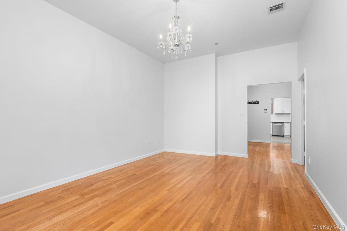 High ceilings featuring a crystal chandelier and light-toned wood-finish flooring
