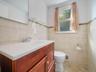 Bathroom featuring a wood-finish vanity with a white integrated sink, full-height wall tiling with a mosaic accent border, and a large wall-mounted mi