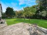 Concrete patio featuring a large level lawn and mature trees