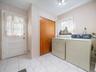 Laundry room featuring white tile flooring, wood-finish closet doors, and an exterior door with inset glass