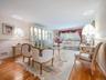 Living space featuring wood-finish flooring, chair rail molding, and a built-in illuminated glass-front display cabinet