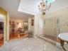 Entryway featuring large-format tile flooring, a recessed ceiling with a decorative chandelier, and a front door with glass sidelights and transom win