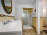 Bathroom featuring a vanity with a white integrated sink, walk-in shower with a sliding glass door, decorative tile backsplash, and tile flooring