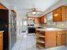 Kitchen featuring wood cabinetry, natural stone countertops with integrated open shelving, tile flooring, and stainless steel appliances