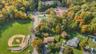 Aerial perspective featuring expansive green space, mature deciduous trees, a baseball diamond, and a tennis court