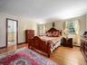 Bedroom featuring wood-finish flooring, dual windows, and an arched entryway