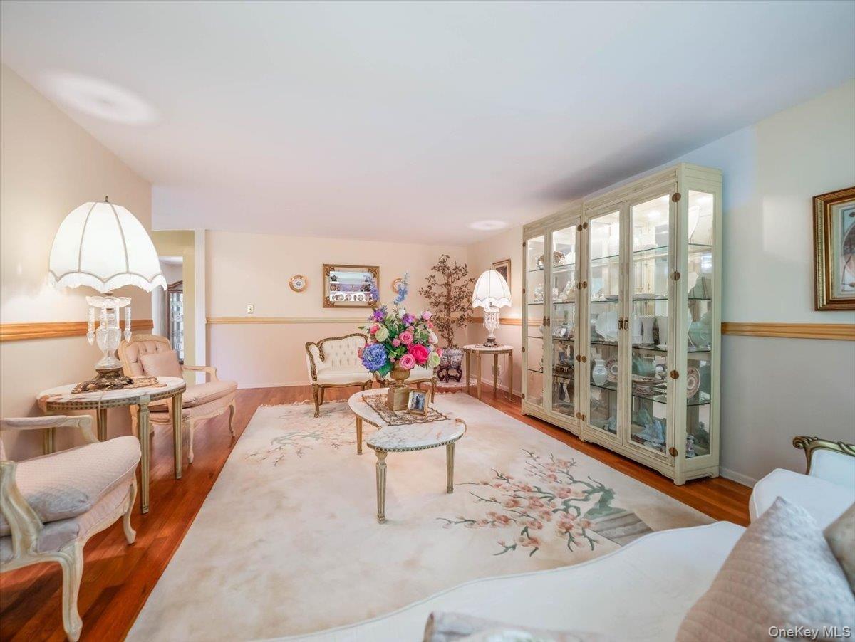 Living area featuring wood-finish flooring, custom built-in glass display cabinetry, and two-tone wall finish with chair rail molding