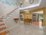 Foyer featuring large-format tile flooring, a curved staircase with white metal railings, wood-finish stair treads, and a crystal-style chandelier