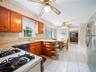 Kitchen featuring natural-finish wood cabinetry, stone-surface countertops, tile backsplash, tile flooring, and stainless steel appliances