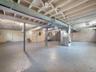Unfinished basement featuring exposed structural ceiling joists, painted concrete flooring, and metal support columns
