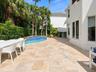 Backyard patio featuring light-toned stone pavers, an in-ground swimming pool with blue tile accents, a raised spa, and mature perimeter landscaping