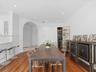 Dining area featuring wood-finish flooring, recessed lighting, a large architectural archway, and a built-in refrigerated wine storage niche