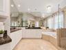 Bathroom featuring a double vanity with stone countertops, tiled soaking tub, walk-in glass-enclosed shower, wall-to-wall mirrors, and crystal light f