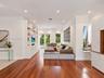 Living area featuring wood-finish flooring, recessed lighting, floor-to-ceiling custom built-in cabinetry, and French doors