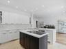 Kitchen featuring white cabinetry with glass-front display panels, central island with a contrasting dark finish, integrated stovetop, recessed lighti