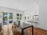 Open-concept dining area featuring wood-finish flooring, recessed lighting, breakfast bar with stone-finish countertop, and dual glass-panel doors