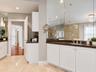 Dual-vanity bathroom featuring white cabinetry, dark stone-finish countertops, wall-to-wall mirror, recessed lighting, and tile flooring