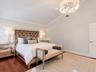 Vaulted ceiling featuring a crystal drum chandelier, wood-finish flooring, and a multi-panel interior door