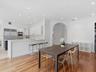 Open-concept interior featuring wood-finish flooring, recessed lighting, and a kitchen equipped with stainless steel appliances, crisp white cabinetry