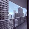 Private balcony featuring glass panel railing and urban skyscraper surroundings